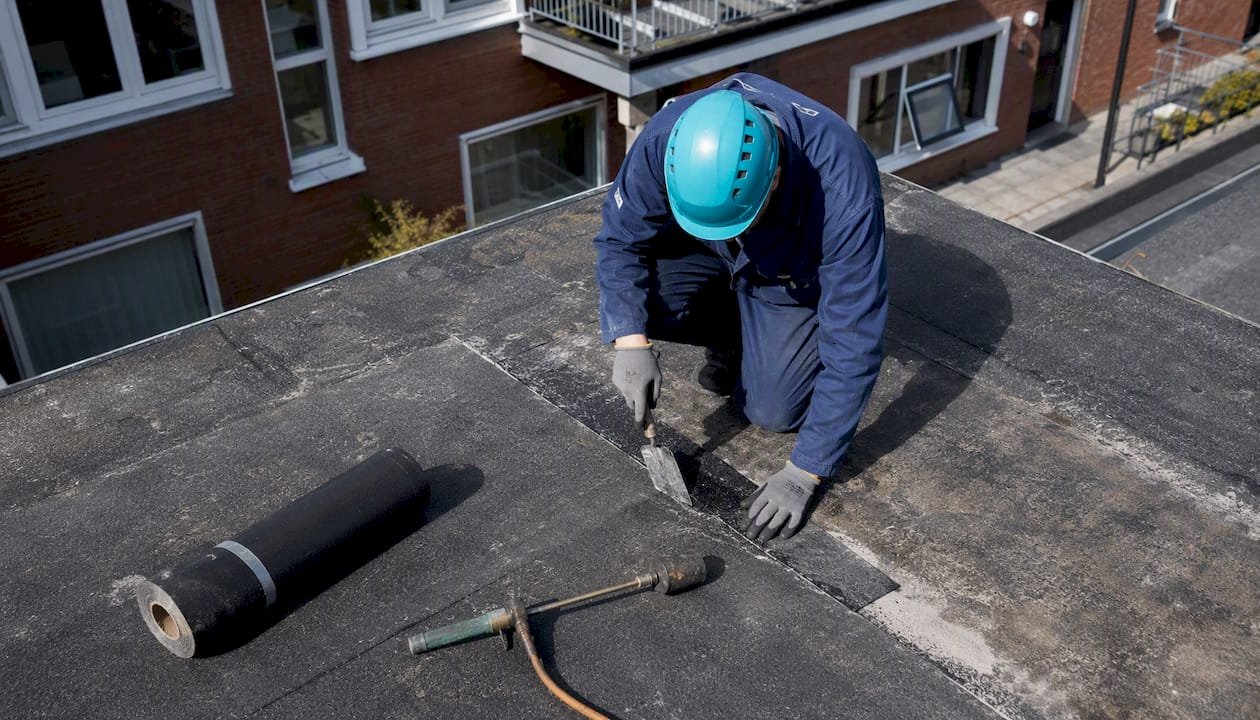 Dakdekker voert herstelwerkzaamheden uit aan het schuine dak van een VvE-woning.
