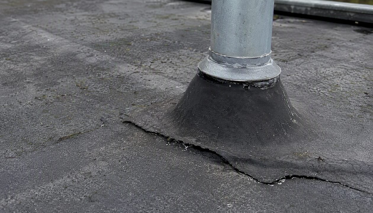 Bitumen dak beschadigd rondom de doorvoer