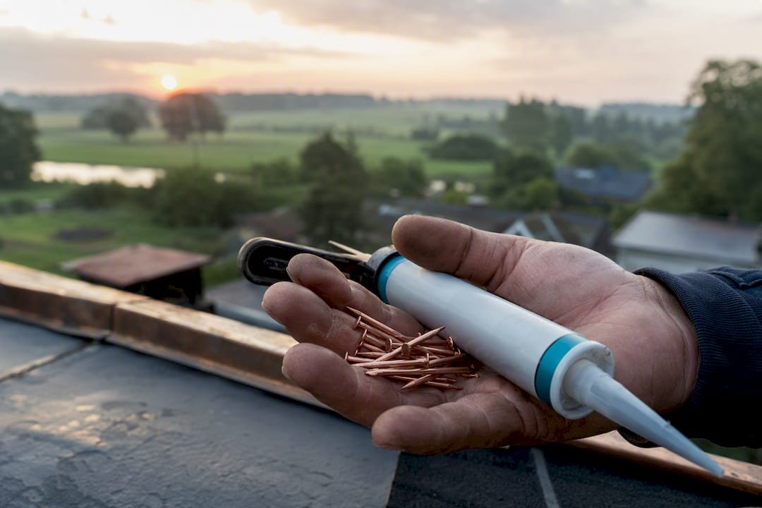 Hand van dakdekker met nagels en kit
