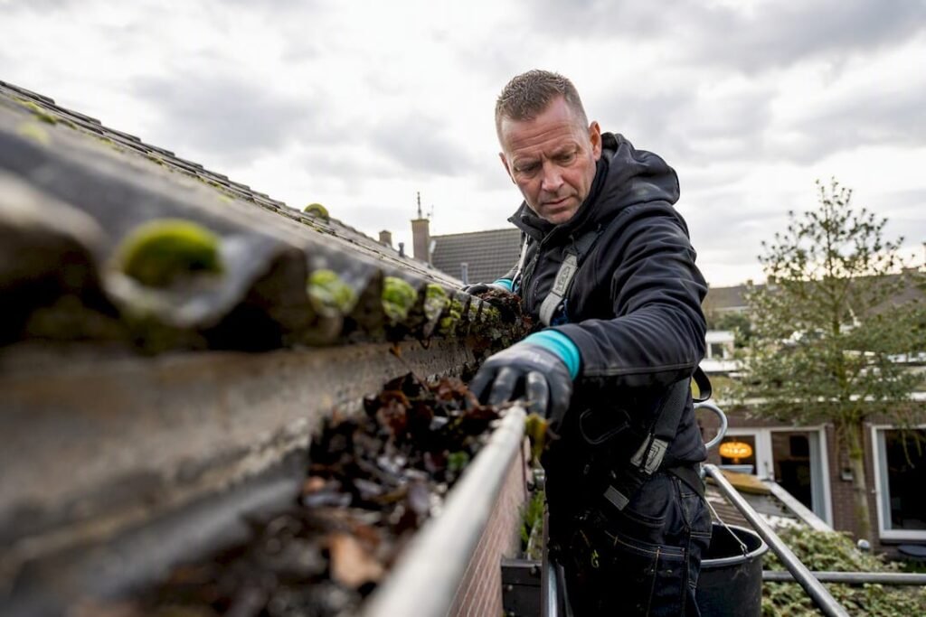 Dakdekker maakt de dakgoot van een woning schoon