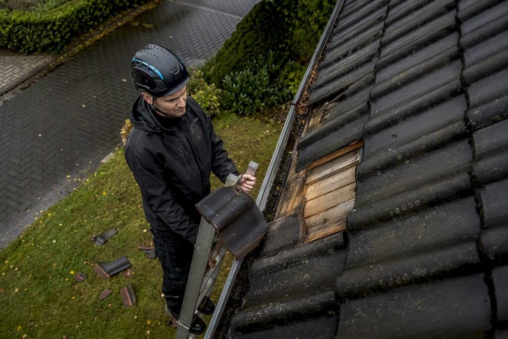 Dakdekker inspecteert stormschade aan woning