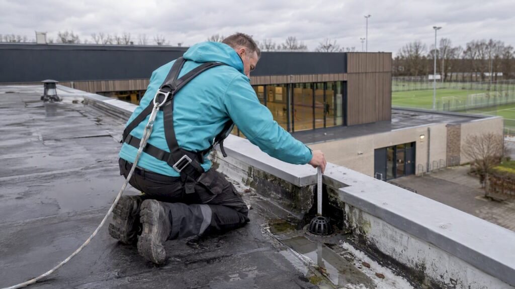 Dakdekker bekijkt dakrand voor onderhoudsplanning