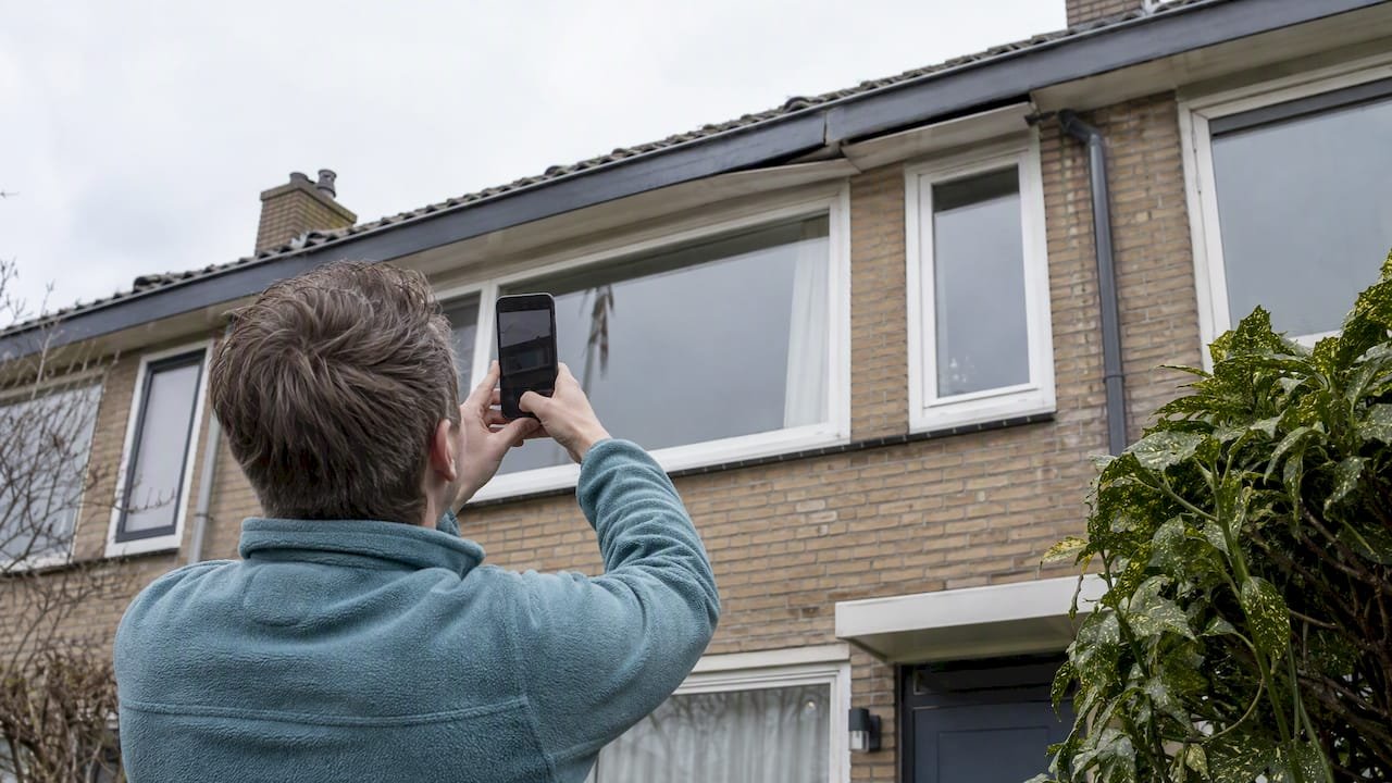 Huiseigenaar maakt foto van dakrand vanaf de grond